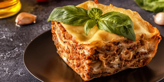 Traditional lasagna made with minced beef bolognese sauce and bechamel sauce topped with basil leaves.